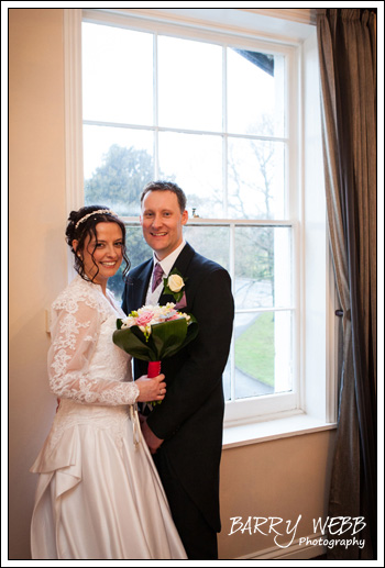 Bride and groom pose in front of the window at Hadlow Manor Hotel in Kent