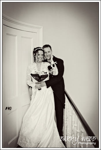 The bride and groom pose at the top of the stairs at Hadlow Manor Hotel in Kent